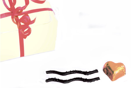 Foil wrapped heart shaped chocolate with an equals sign and a box with red ribbonsの写真素材