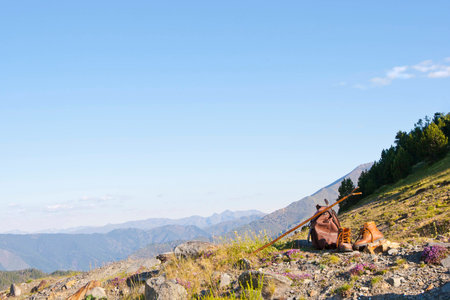 Hiking Boots and Hazel Thumb Stick Lie Beside a Knapsack with View of Mountains Beyondの写真素材