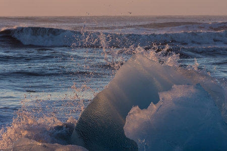 Waves breaking on large glacial ice forms on ice beach in winter in Iceland