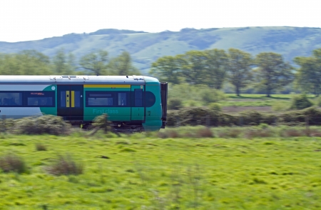 Electric train speeding though hazy English countryside with Sussex South Downs in backgroundのeditorial素材