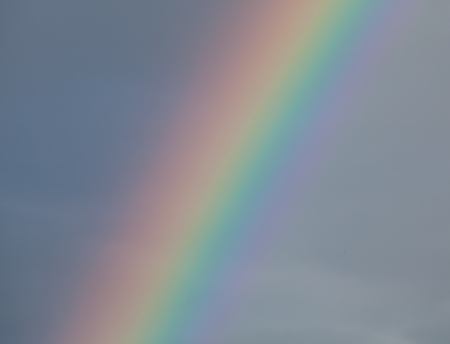 Detail of rainbow against dark cloud, showing full colour spectrum.の写真素材