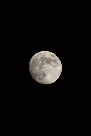 Waxing gibbous Moon, portrait orientated image in photo dimensions with Moon isolated on black background with text or copy space.の写真素材