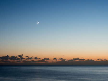 Moon showing Earthshine at dusk over English Channel from Sussex coast.の写真素材