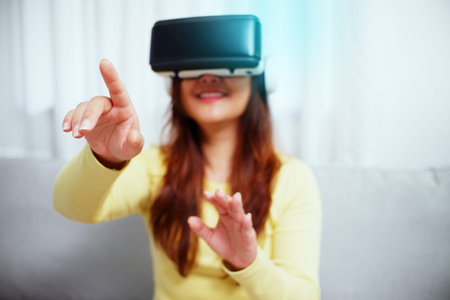 Young asian woman wearing virtual reality glasses, hand touching the air. VR headset. VR concept.