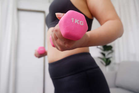 Young Asian women doing exercise at home using dumbbell exercise arms and upper body.の写真素材