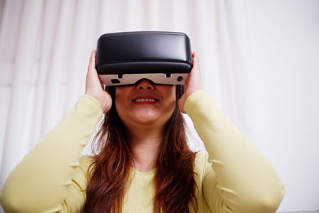 Young asian woman wearing virtual reality glasses at home. VR headset. VR concept. Metaverse.