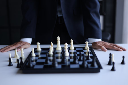 Businessman wearing suit, playing chess, game of strategy, leadership and management concept.の写真素材