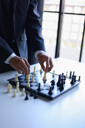 Businessman wearing suit, playing chess, game of strategy, leadership and management concept.の写真素材