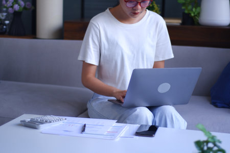 Young Asian women remote work from home analyzing data, calculating, studying.の写真素材