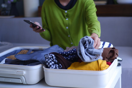 Young women folding clothes, packing luggage for holiday trip.の写真素材