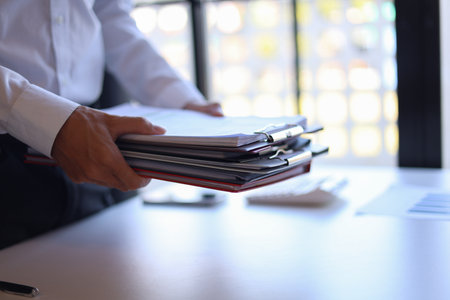 Businessman working in office carrying stack of documents.の写真素材