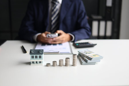 Investing in Real Estate, Real estate agent or investor calculating, planning, analyzing financial data for property investment. Themes of saving, investing, financial aspects of purchasing a home.の写真素材