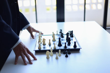 Businessman wearing suit, playing chess, game of strategy, leadership and management concept.の写真素材