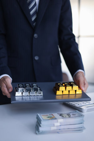 Businessman investing in precious metals gold and silver to diversify portfolios hedge against inflation and currency depreciation.の写真素材
