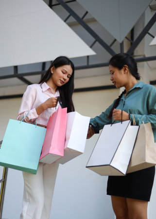 Two female friends happily shopping together at a mall.の写真素材