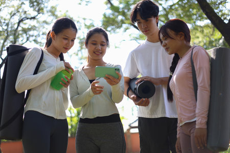 Group of friends sharing online content in the park after exercise.の写真素材