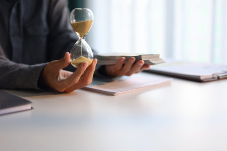 Time and money concept. Businessman holding cash and sand clock imply growth of income, saving or...