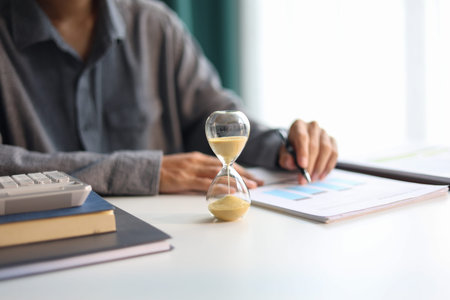 Selective focus on Sand Clocks. Businessman working at office desk. Time management concept.