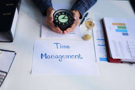 Time management concept. Businessman working on office desk with stack of documents, running sand clock and clock on the table.の写真素材