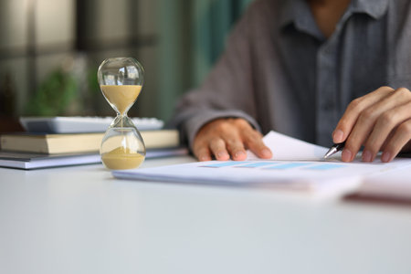 Selective focus on Sand Clocks. Businessman working at office desk. Time management concept.の写真素材