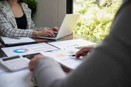 Businesswoman, entrepreneur, accountant working on financial report on desk using calculator,...