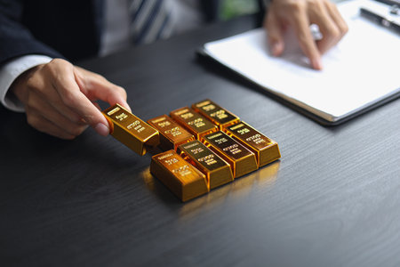 Gold investment Concept. Businessman working on financial planning and gold investment analysis with bullion on desk.の写真素材