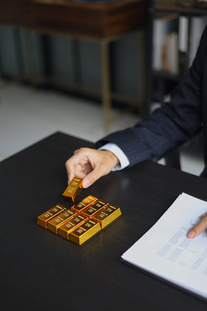 Gold investment Concept. Businessman working on financial planning and gold investment analysis with bullion on desk.