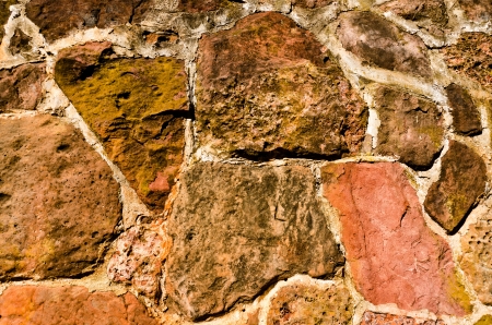 Side of an old stone building built with rocks of varied colors makes a highly textured, colorful backgroundの写真素材