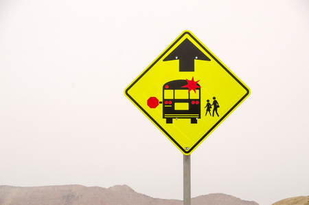 Brightly colored sign to warn of a school bus stop aheadの写真素材