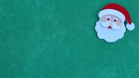 felt crafted Santa Claus face with hat, beard and mustache on a festive green background with copy spaceの写真素材