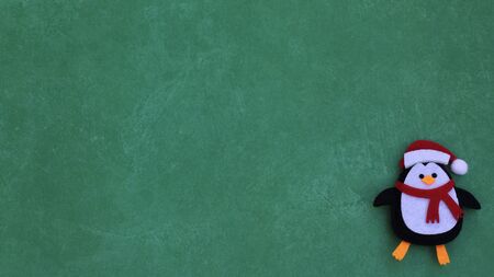felt handmade crafted penguin wearing a scarf and Santa Claus hat on a festive green background with copy spaceの写真素材