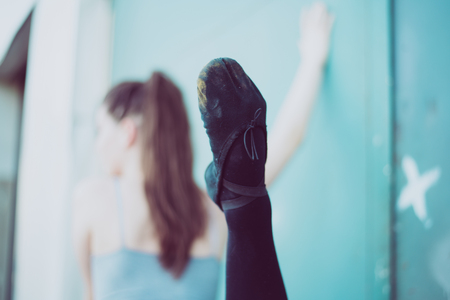 Young dancer in black clothes training in front of the turquoise blue doorの写真素材