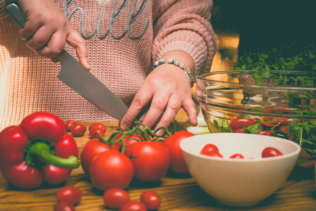Beautiful plus size woman making fresh salad in the kitchenの写真素材
