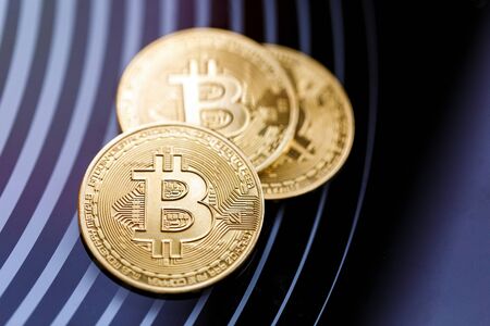 Three gold coins bitcoin on a black background.の写真素材