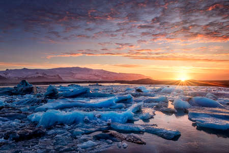 sunset in a glacial lagoon under the icebergの写真素材