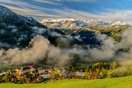 autumn landscape with colorful trees and snowy mountains in the background in Dolomitesの写真素材