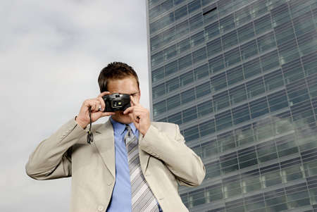 Young businessman with camera in his hands taking pictureの写真素材