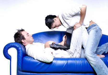 Young couple sitting in a sofa using a laptop