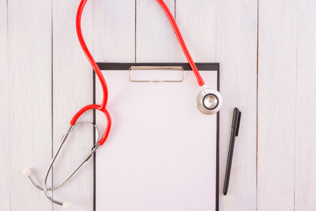 Stethoscope,note pad,pen on wooden desk as medical conceptの写真素材