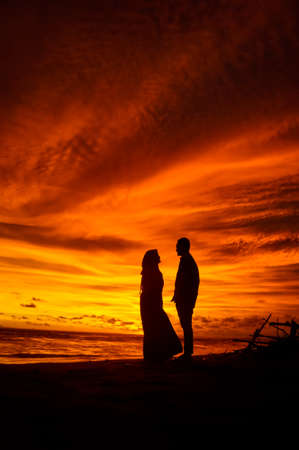 Yogyakarta - Indonesia - 04 April 2020: silhouette couple on the beach at sunset, very romantic, wear hijab, Muslim. low-exposure techniques.のeditorial素材
