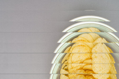 Flat lay of snack, Crispy potato chip are served in glass bowl over gray background.の写真素材