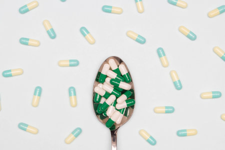 Pharmaceutical and health concept, Antibiotic capsules green white in spoon and spilling on floor.の写真素材