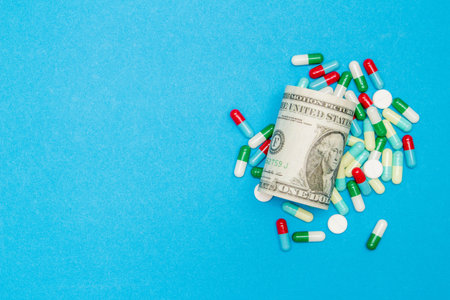 Pharmaceutical and health concept, Antibiotic capsule pill and dollar bill on light blue background.