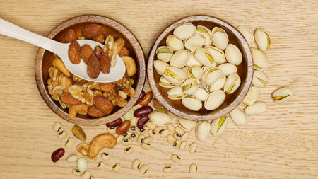 Flat lay of healthy grain concept, Pistachios and almond in wooden bowl and beans on wood table.の写真素材