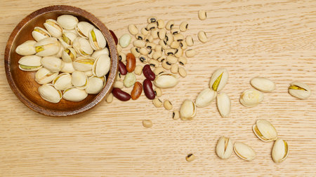 Flat lay of healthy grain concept, Pistachios in wooden bowl and various beans on wood table.の写真素材