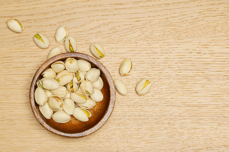 Flat lay of healthy grain concept, Pistachios in wooden bowl on wood table.の写真素材
