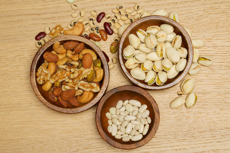 Flat lay of healthy grain concept, Pistachios and almond in wooden bowl and beans on wood table.の写真素材