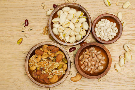 Flat lay of healthy grain concept, Pistachios almond and various bean in wooden bowl on wood table.の写真素材