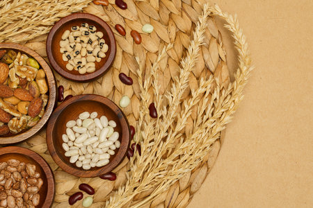 Flat lay of healthy grain concept, Various bean and almond in wooden bowl wheat on brown background.の写真素材