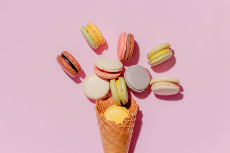 French dessert concept, Colorful macarons are served in waffle cone and falling on pink background.の写真素材
